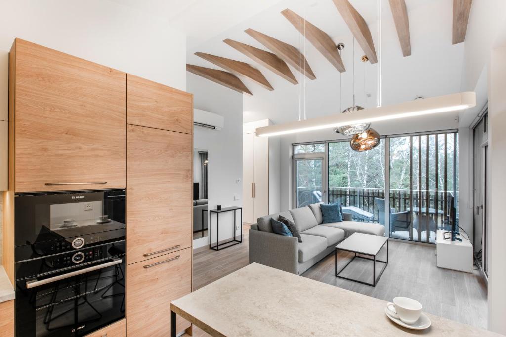 eine Küche und ein Wohnzimmer mit Sofa und Tisch in der Unterkunft Aura Nida in Neringa