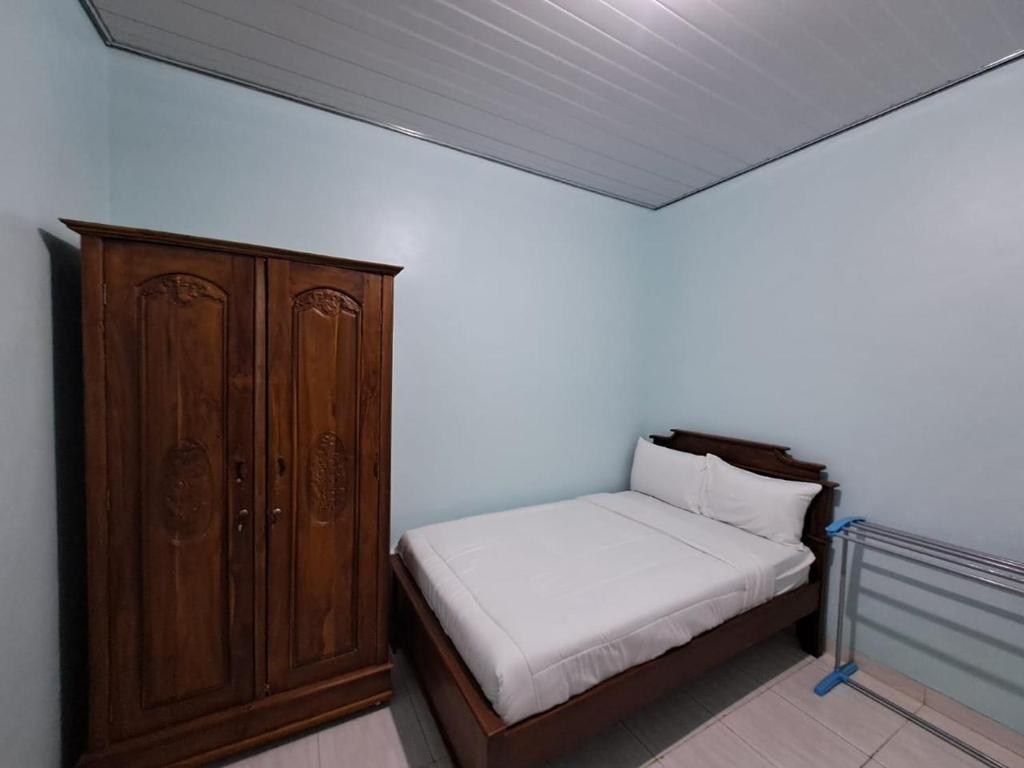 een slaapkamer met een bed en een houten kast bij OYO 93695 Guest House Riharti Syariah in Bandar Lampung