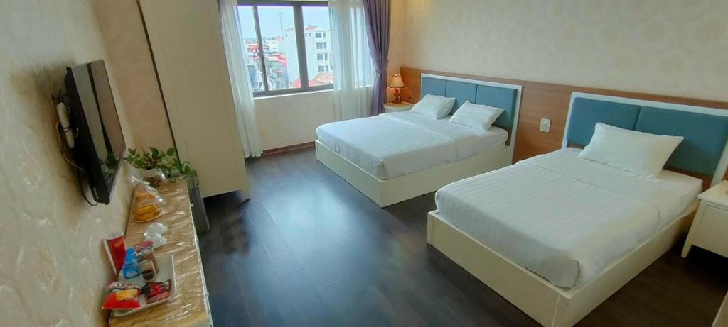um quarto de hotel com duas camas e uma televisão de ecrã plano em DOMINIC HOTEL em Hòa Ðình