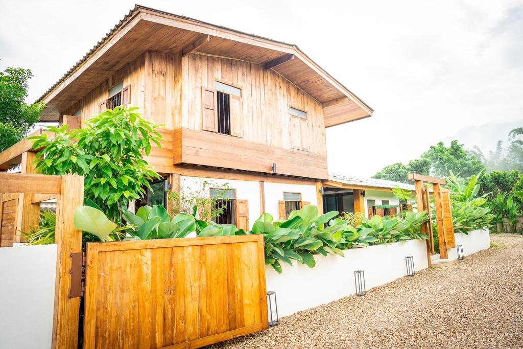 a wooden house with a fence and plants at Baan Inn in Chiang Dao