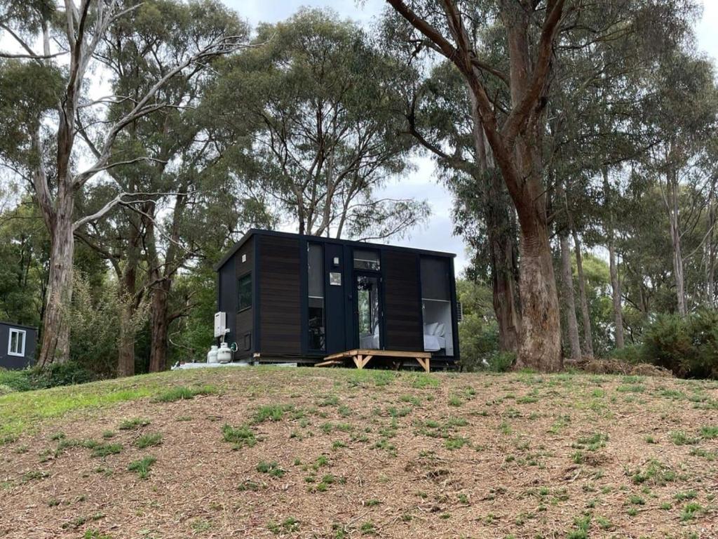 a black tiny house sitting on top of a hill at Longmore Estate in Daylesford