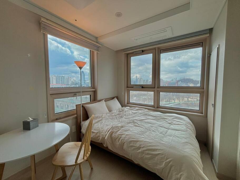 a bedroom with a bed and a table and windows at Guil Property in Seoul