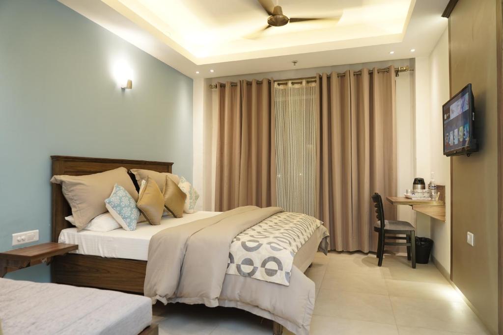Schlafzimmer mit einem Bett, einem Schreibtisch und einem TV in der Unterkunft HOTEL CENTRA in Mohali