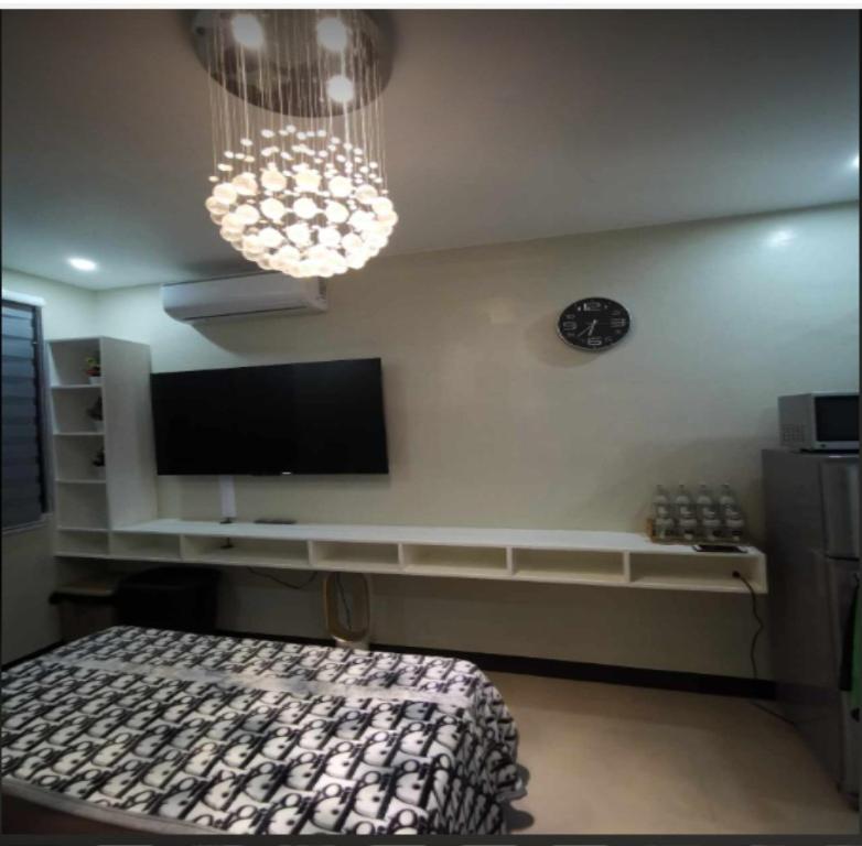 een slaapkamer met een televisie en een klok aan de muur bij Villa De Gracia in Manilla