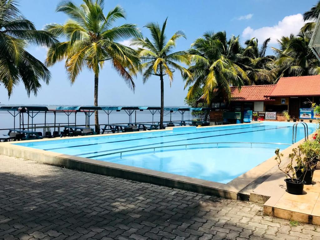 a swimming pool with palm trees and the ocean at New Saniro Lagoon Deck in Katunayaka