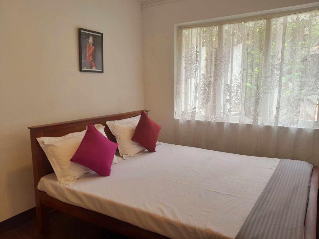 a bedroom with a bed with pink and white pillows at Laliz in Hikkaduwa