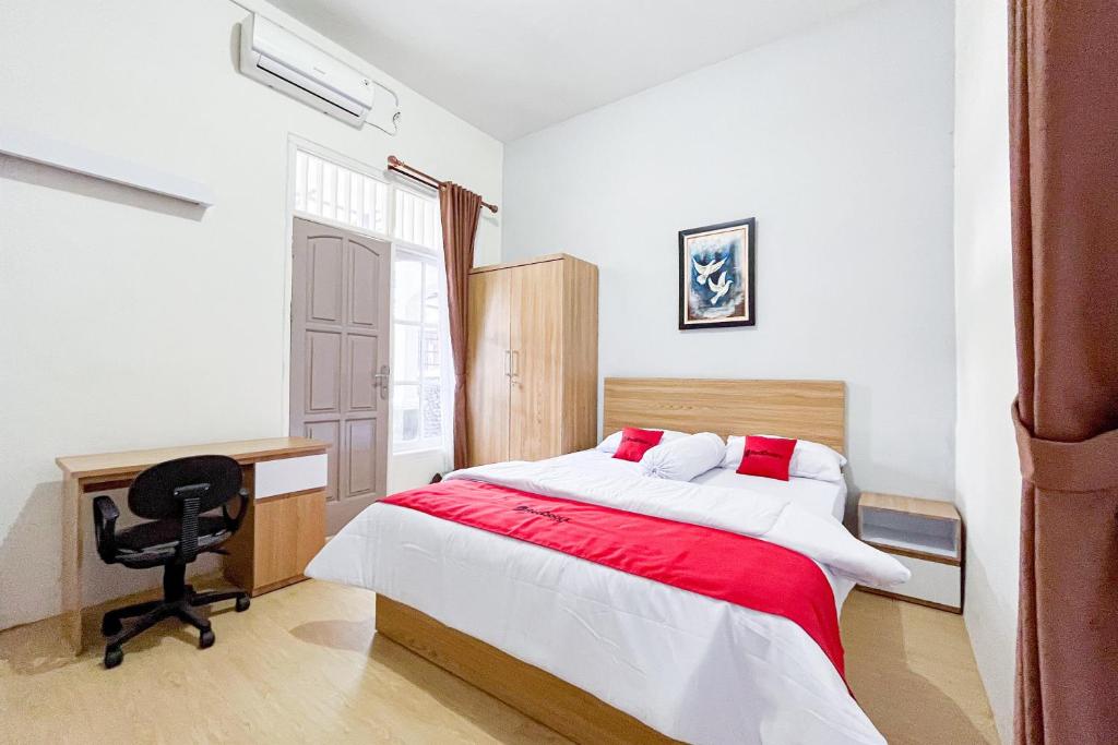 um quarto com uma cama, uma secretária e uma cadeira em RedDoorz Syariah @ Jl. Candi Kalasan em Blimbing