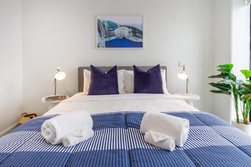 - une chambre avec un lit bleu et blanc et des serviettes dans l'établissement Greek Island Inspired 2 Bed room 1 Bath Townhouse, à Christchurch