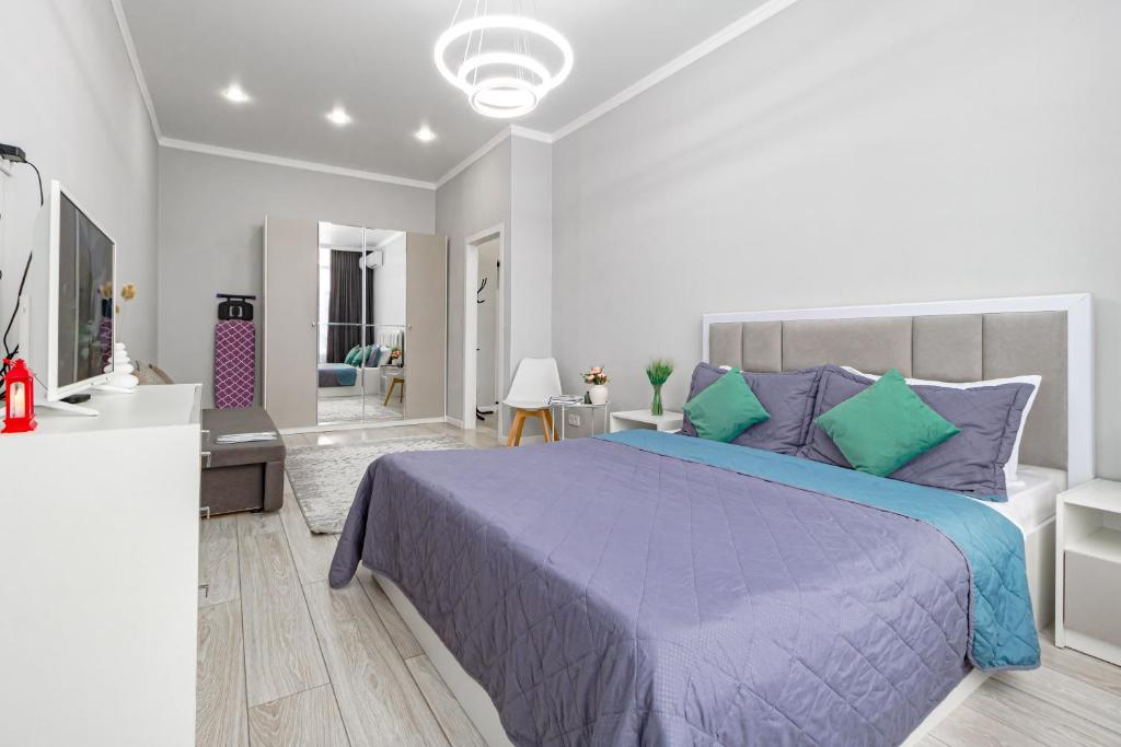 a bedroom with a purple bed and a living room at Apart Astana, Комплекс Парасат 226, рядом с ботаническим садом, Барыс арена, Астана арена in Astana