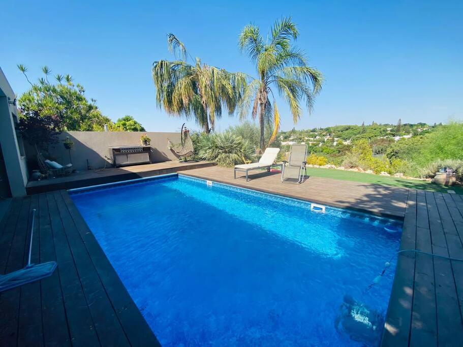 a blue swimming pool with a patio and palm trees at קשת בענן in Modi'in-Maccabim-Re'ut