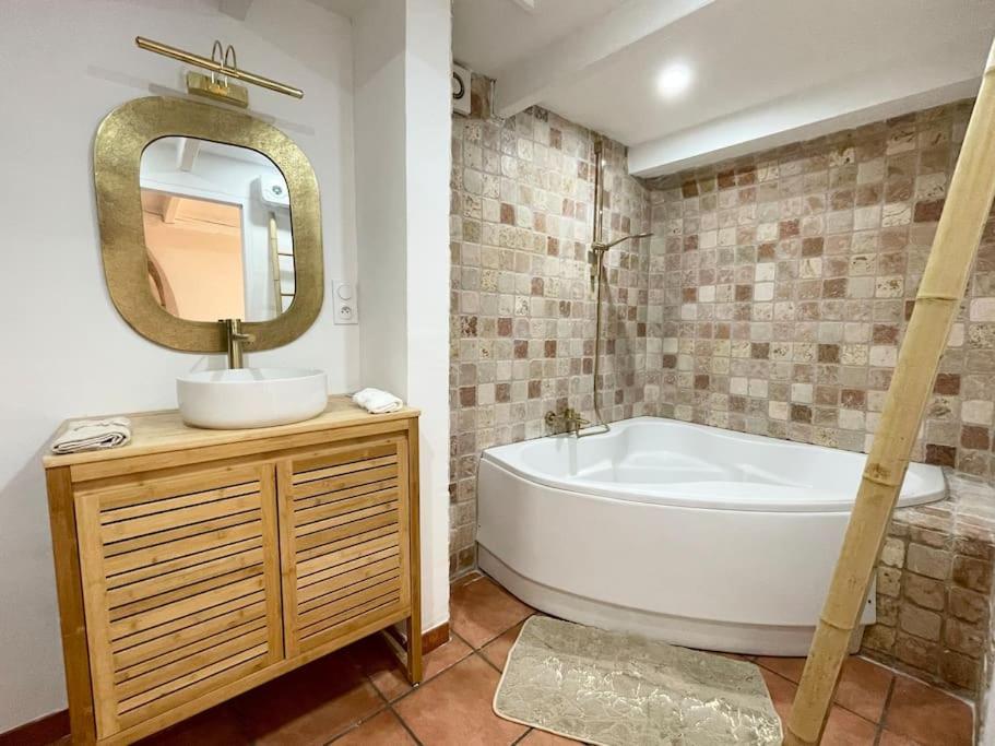 une salle de bain avec une baignoire, un lavabo et un miroir dans l'établissement Studio 40m2 au cœur du village, à Cornillon-Confoux