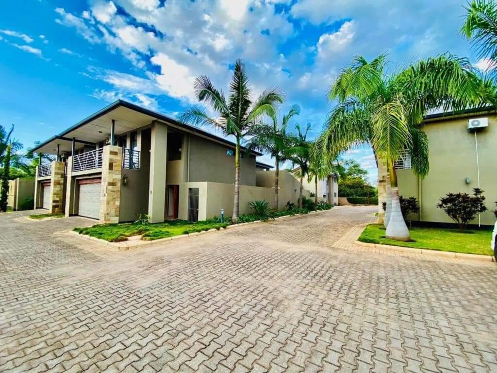 a house with palm trees in the driveway at Marangu (3bedroom) in Lusaka