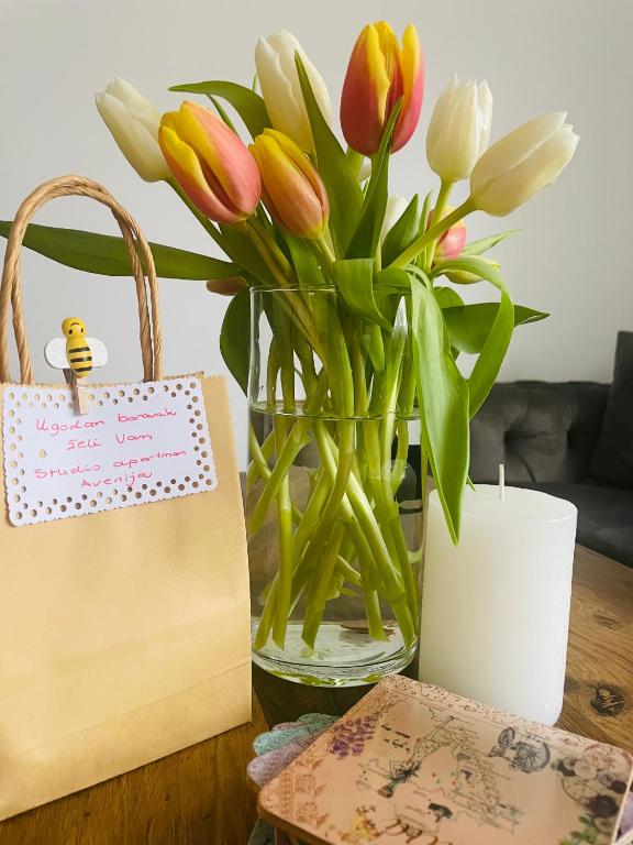 a vase of flowers and a bag on a table at Studio apartman Avenija *** in Slavonski Brod