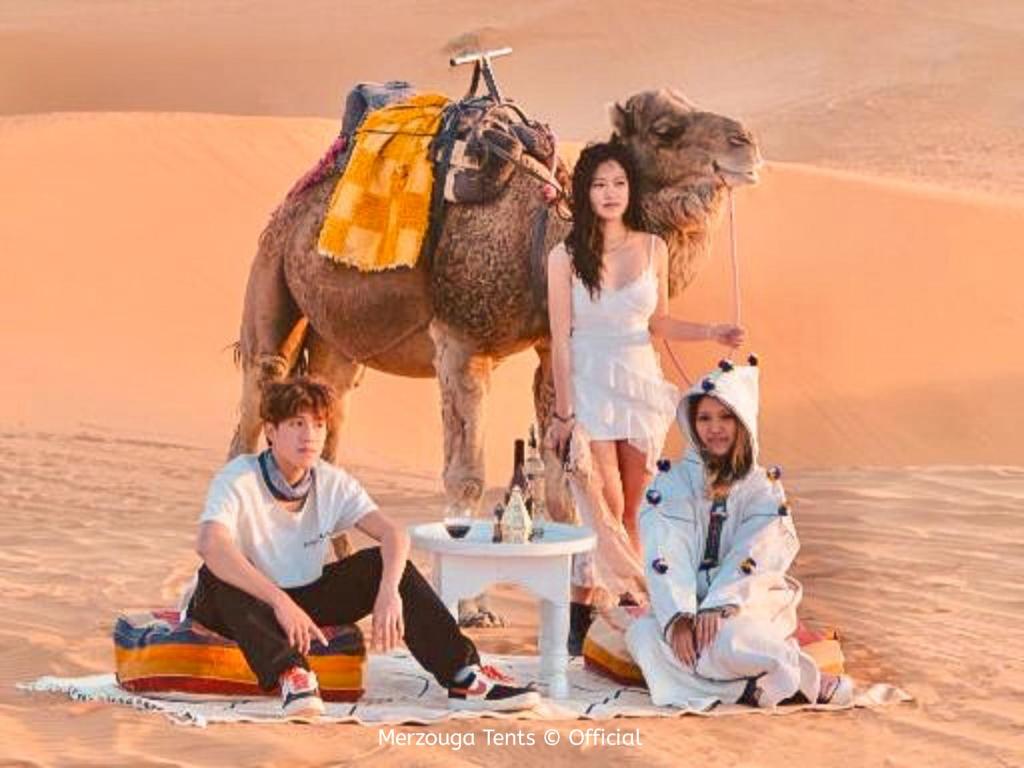 a group of people in the desert with a camel at Merzouga Tents © Official in Merzouga