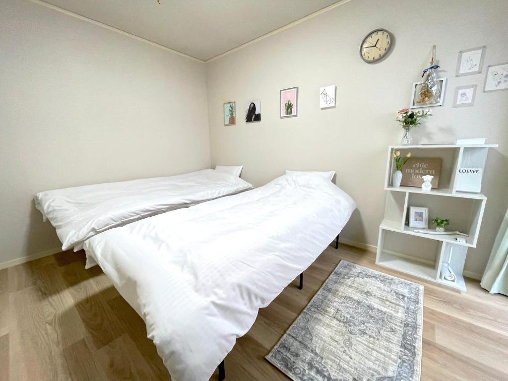 een slaapkamer met een bed met witte lakens en een klok bij Gest Residence EDORIVER Airport Line Self check in in Tokyo
