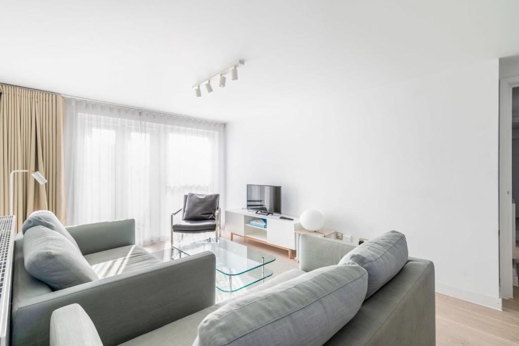ein Wohnzimmer mit einem Sofa und einem Glastisch in der Unterkunft Belgravia Apartment 45 in London