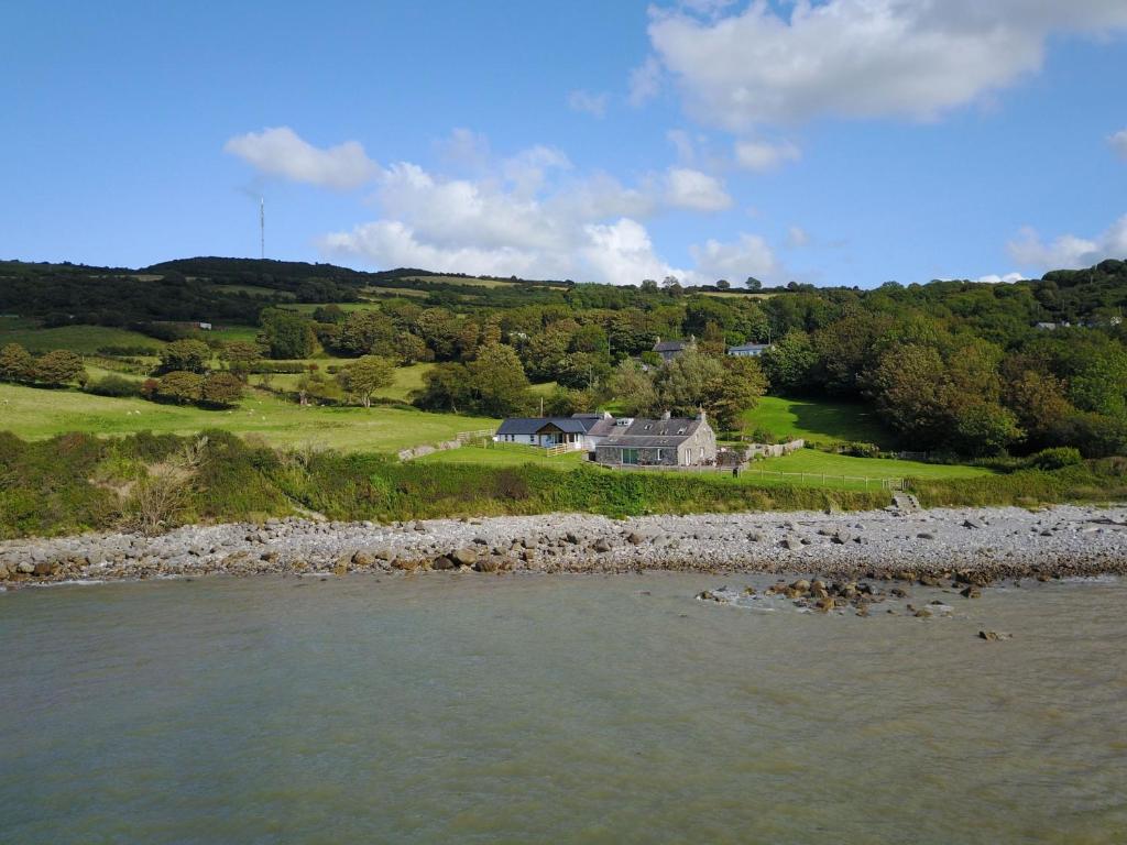 a house on a hill next to a body of water at Ty Gwyn in Llanddona