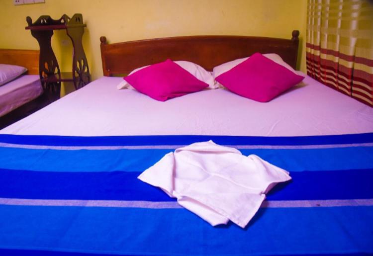a bed with purple and white pillows on it at WK Villa in Ella