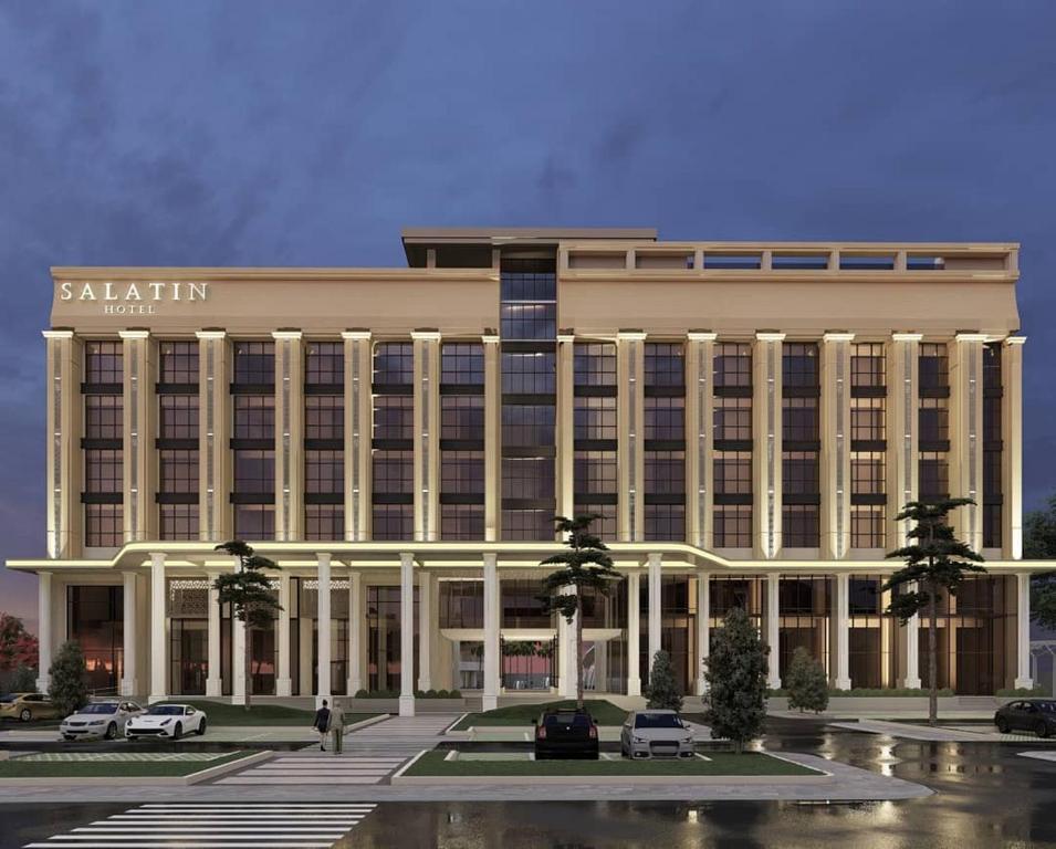 un grand bâtiment avec des voitures garées devant lui dans l'établissement Salatin Hotel Palembang, à Palembang