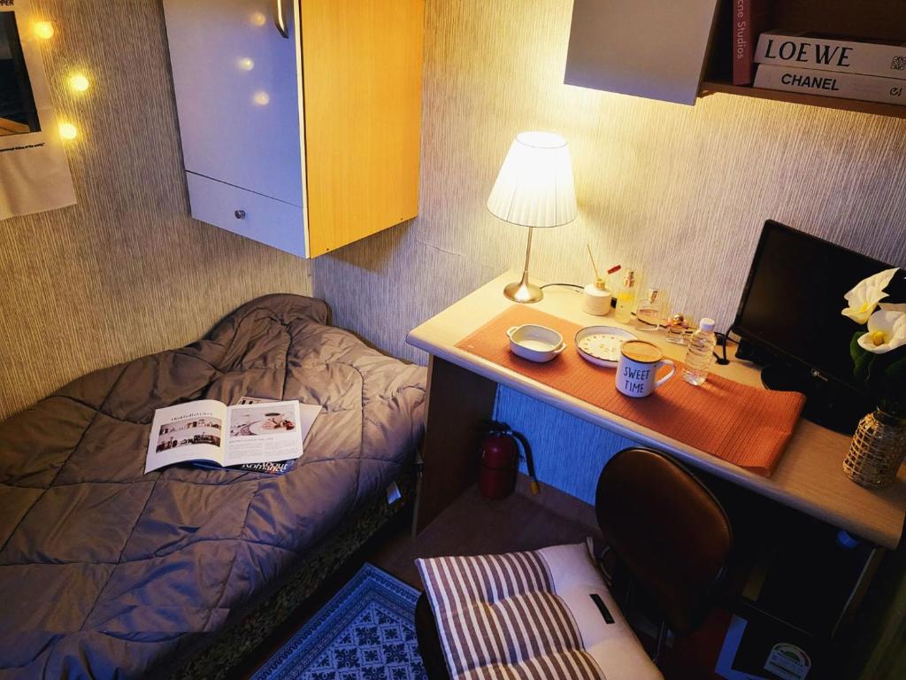 a small room with a desk and a bed with a lamp at The Stay Hill in Seoul