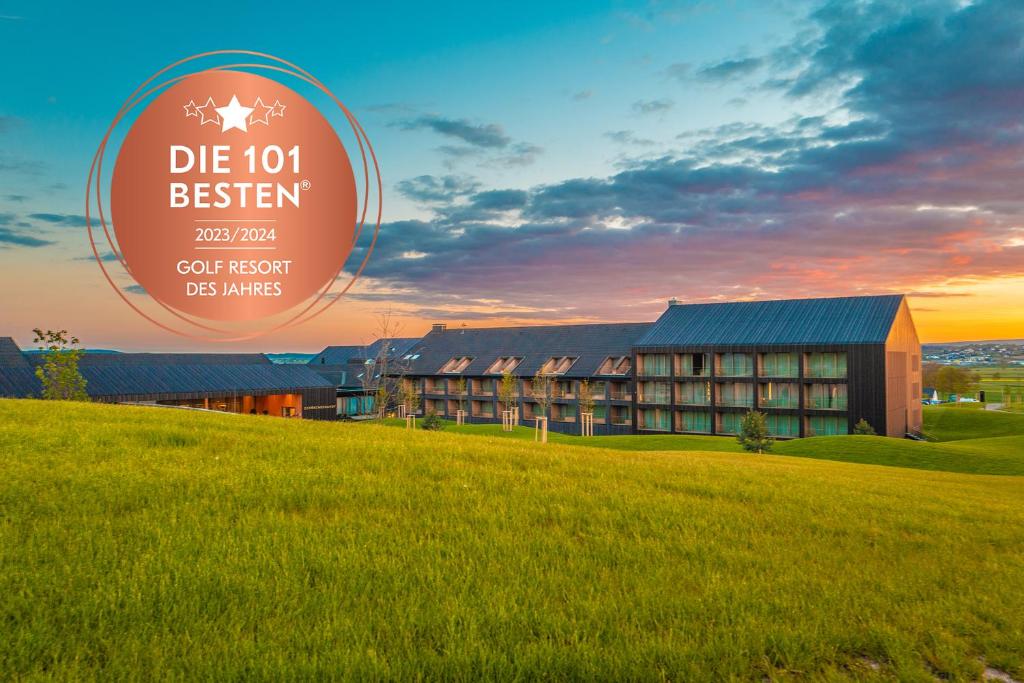 un edificio con un campo de hierba delante de él en Der Öschberghof Golf Resort des Jahres 2024 en Donaueschingen