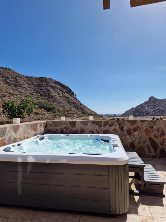 een hot tub op een patio met bergen op de achtergrond bij Amazing cozy Villa Hugo Tauro with Jacuzzi, Pool, Wi-Fi in Mogán