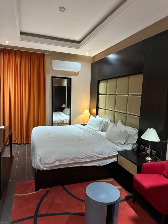 een hotelkamer met een groot bed en een rode bank bij Rich Bridge Hotel in Abuja