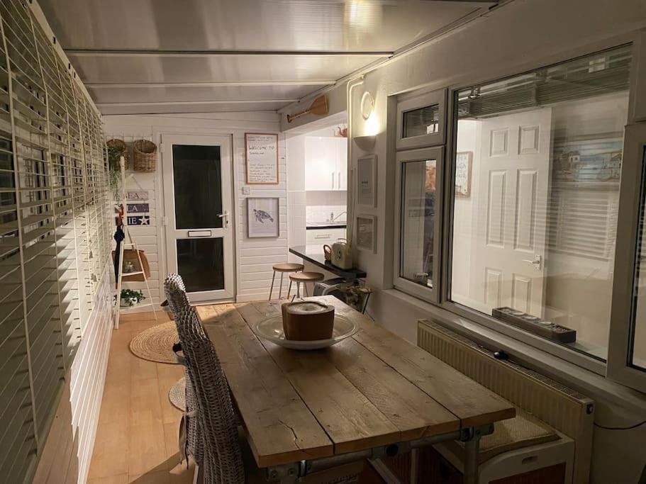 ein Esszimmer mit einem Holztisch und einem Fenster in der Unterkunft Shoreline hideaway - next to the beach in Little Holland