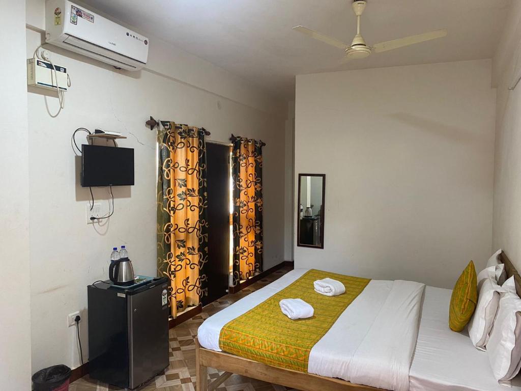 a bedroom with a bed with yellow curtains in it at Calangute Beach Prime in Calangute