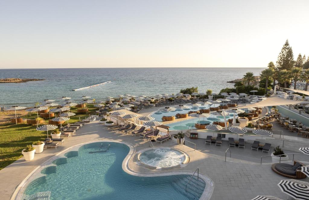 eine Luftansicht eines Resorts mit Pool und Sonnenschirmen in der Unterkunft King Jason Protaras - Designed for Adults in Protaras