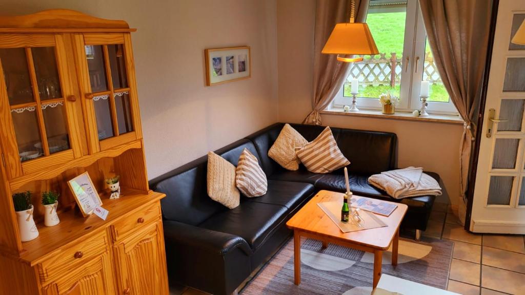 een woonkamer met een zwarte leren bank en een tafel bij Burhave Gästehaus 8 in Butjadingen