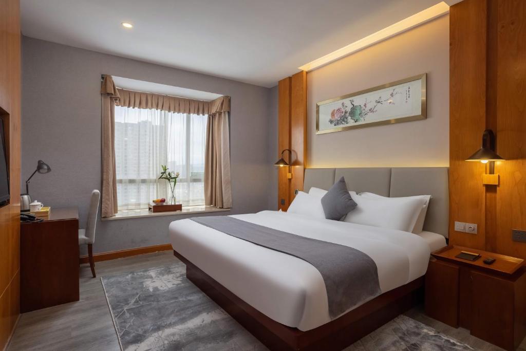 a bedroom with a large white bed and a window at ALLIN HOTEL in Shenzhen