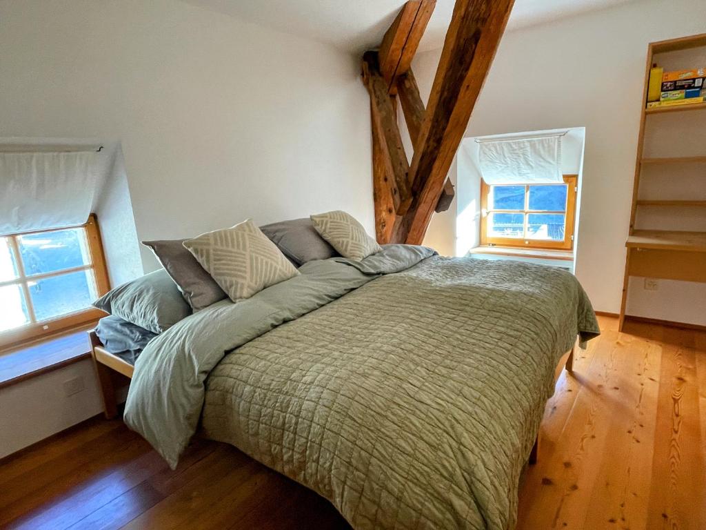 a bed in a room with two windows at Casa Barbun - Soglio GR in Soglio