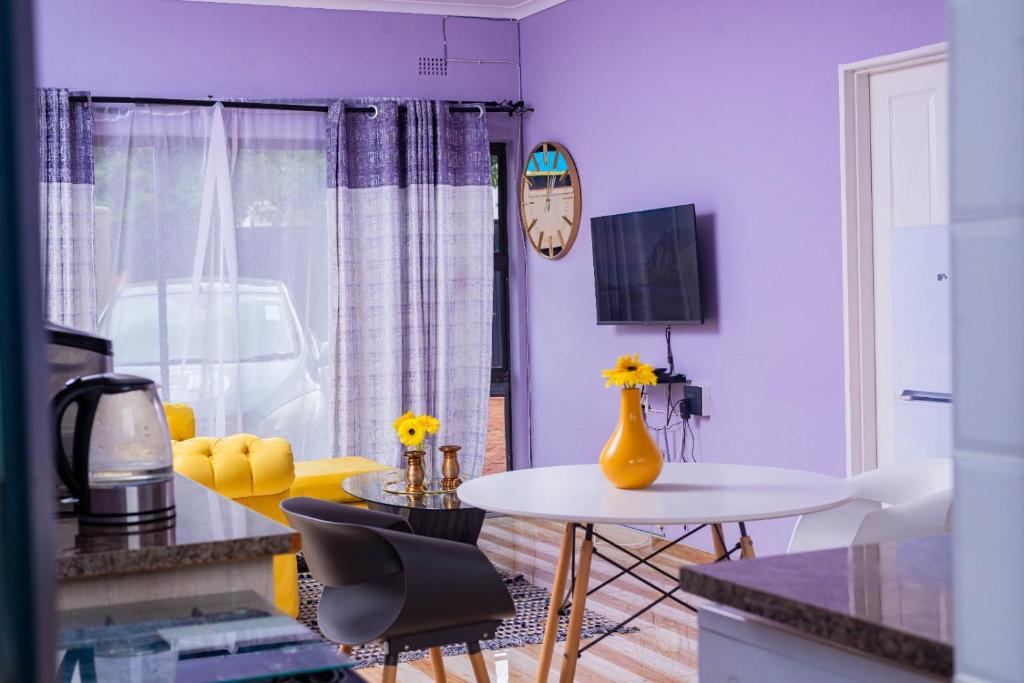 a living room with purple walls and a white table at The Crescent Byo in Bulawayo