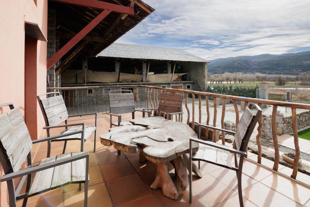een patio met een tafel en stoelen op een balkon bij Masia d'en cot in Puigcerdà