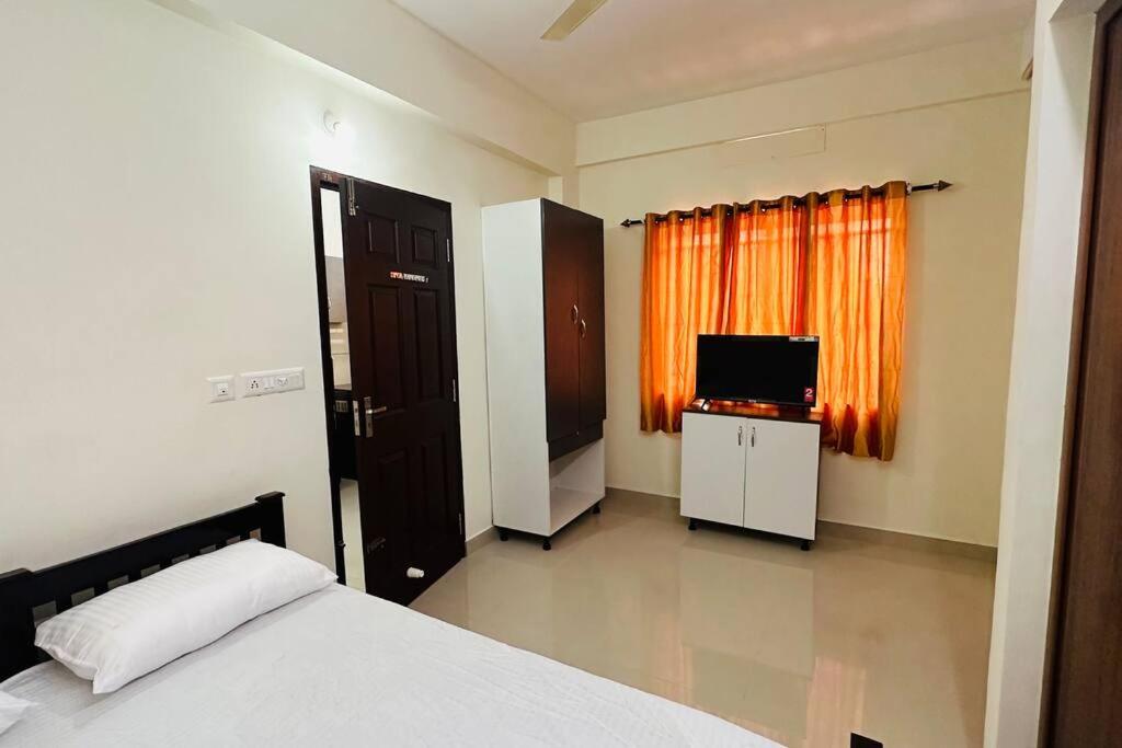 a bedroom with a bed and a flat screen tv at Peaceful Living Solo Suites in Ernakulam