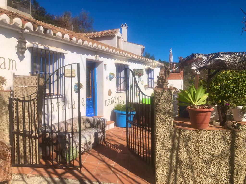 een poort naar een wit huis met potplanten bij Casa Ganesha in Comares