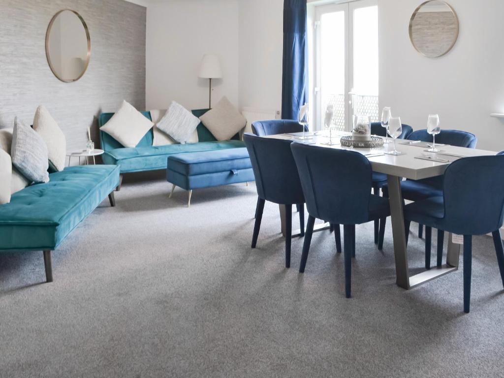 a dining room with a table and blue chairs at The Bandstand Sea View in Blythe