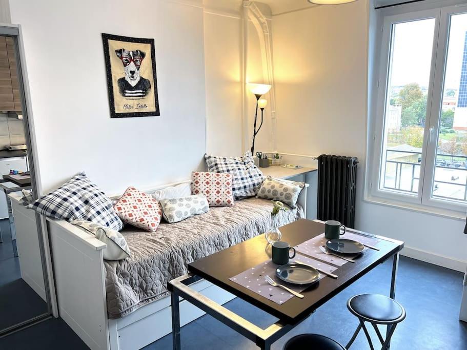 een woonkamer met een bank en een tafel bij Studio proche transports in Choisy-le-Roi