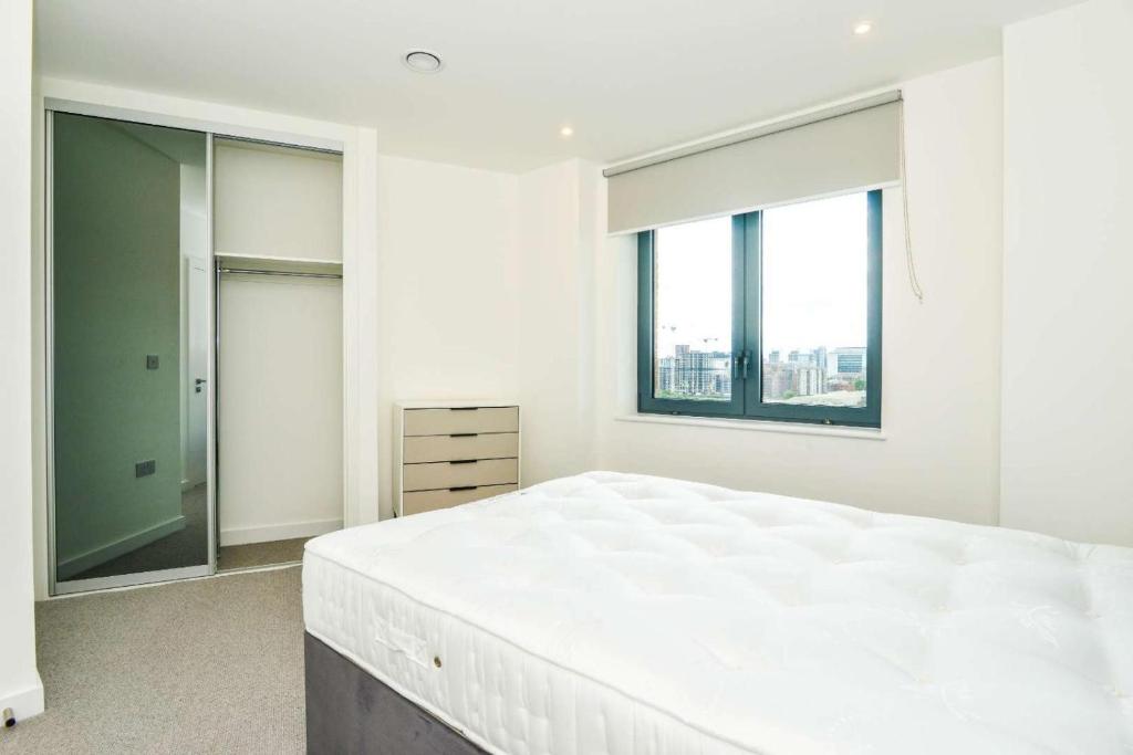 1 dormitorio blanco con 1 cama grande y 2 ventanas en Luxury 2 Bedroom Apartment East London, en Londres
