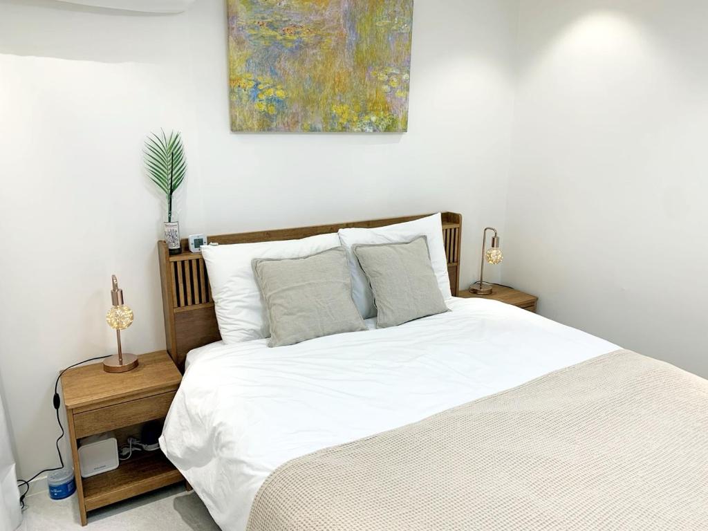 a bedroom with a white bed and a painting on the wall at Comma 2, Cozy Semi-basement in Seoul