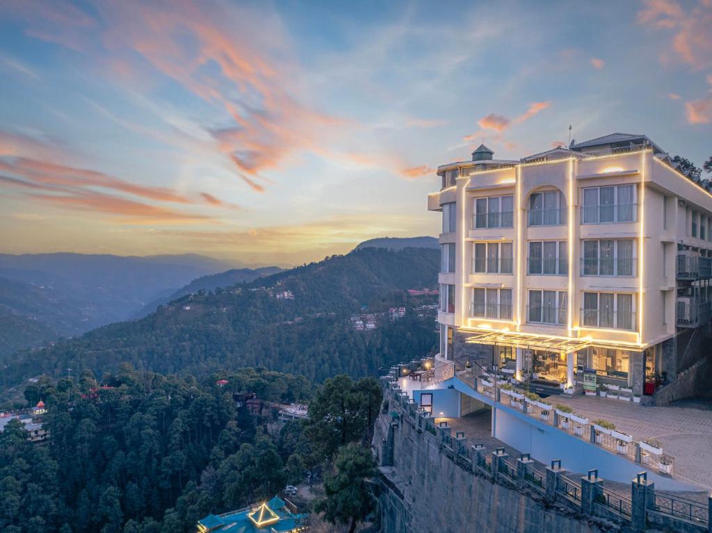 un edificio al lado de una montaña al atardecer en Echor Shimla Hotel - The Zion en Shimla