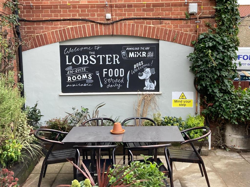 a table and chairs with a sign on a wall at The Lobster in Sheringham