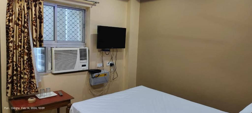 a bedroom with a bed and a window and a television at Hotel JM International (A Unit of Hotel Care Plaza) in Puri