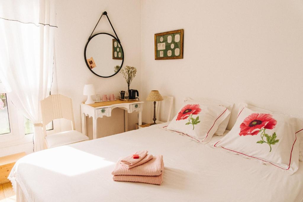 - une chambre avec un lit blanc orné de fleurs rouges dans l'établissement La Petite Maison, à Marseille