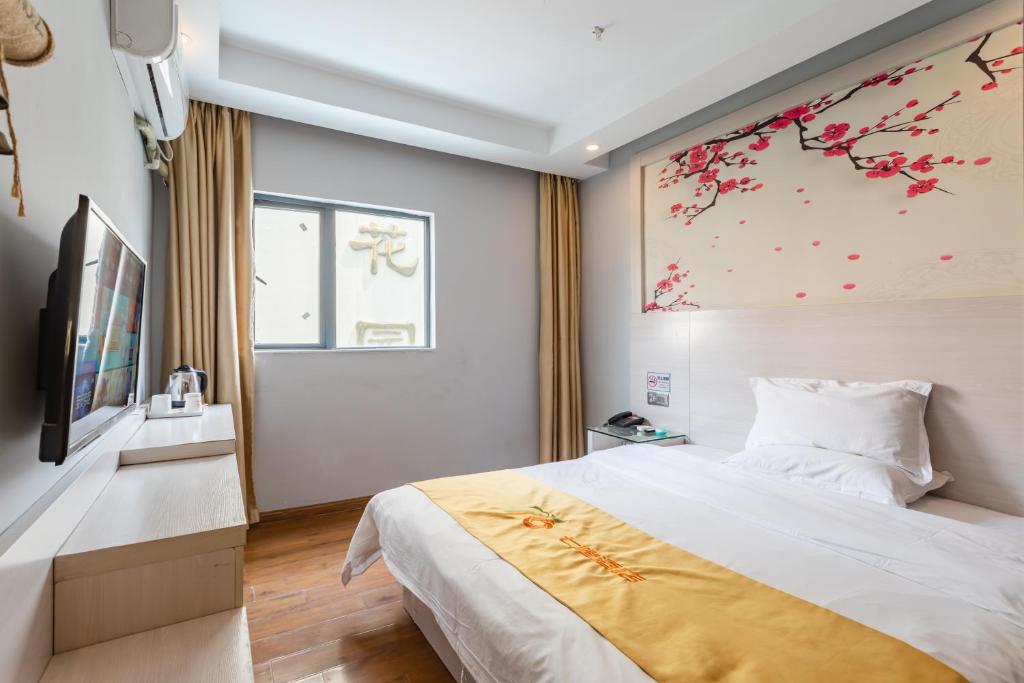- une chambre avec un grand lit et une peinture murale dans l'établissement Seven Orange Hotel, à Shenzhen