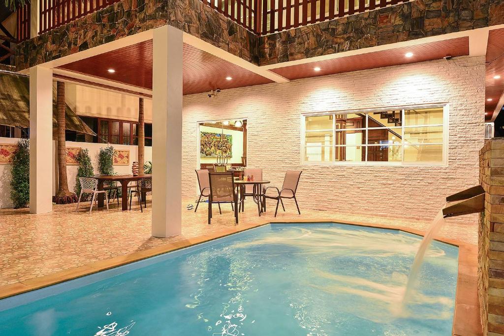 a swimming pool in a house with a table and chairs at Group Getaway Patong House in Patong Beach