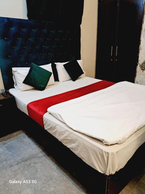 a bedroom with a bed with white and green pillows at Lord Family Hotel in Lahore