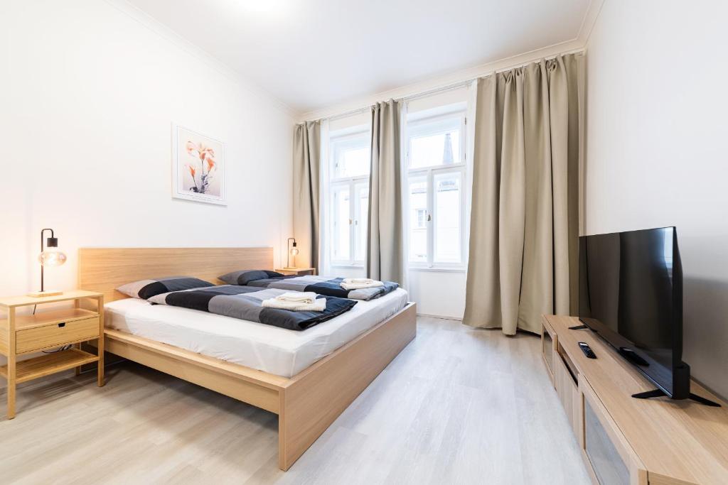 een slaapkamer met een bed en een flatscreen-tv bij Apartments Borivojova 63 in Praag