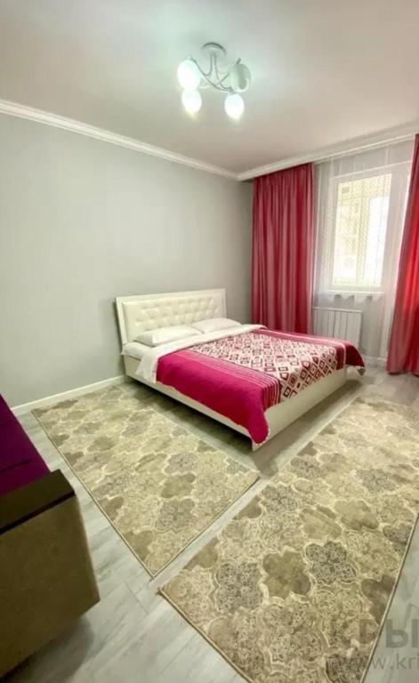 een slaapkamer met een groot bed met rode gordijnen bij ЖК Алмалы in Alma-Ata